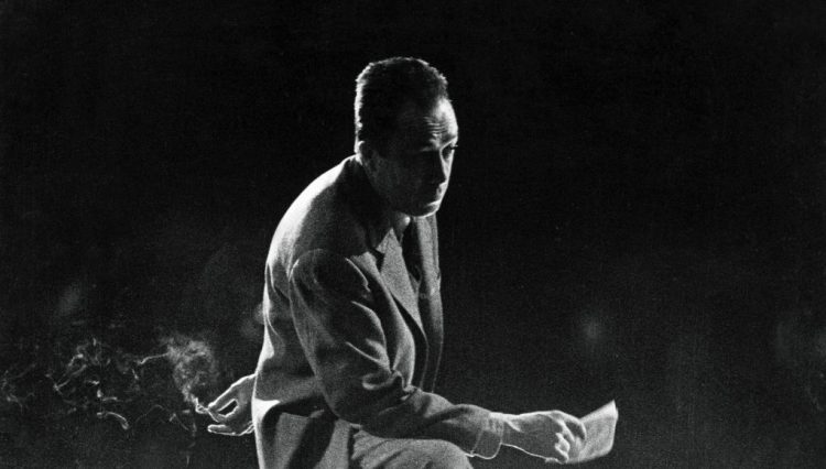 1959 - Albert Camus Directs His Play 'Les Possedes'. Les répétitions au théâtre Antoine de la pièce 'Les possédés' d'Albert Camus, mise en scène par l'auteur : attitude d'Albert CAMUS sur la scène du théâtre, un pied sur une chaise et une cigarette à la main, sous la lumière des projecteurs. (Photo by Jack Garofalo/Paris Match/Getty Images)
