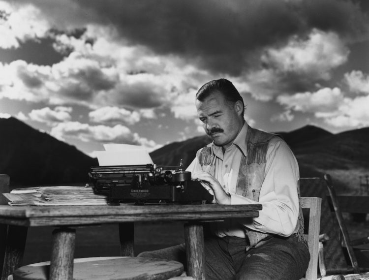 7th October 1939:  EXCLUSIVE American writer Ernest Hemingway (1899 - 1961) works at his typewriter while sitting outdoors, Idaho. Hemingway disapproved of this photograph saying, 'I don't work like this.'  (Photo by Lloyd Arnold/Hulton Archive/Getty Images)